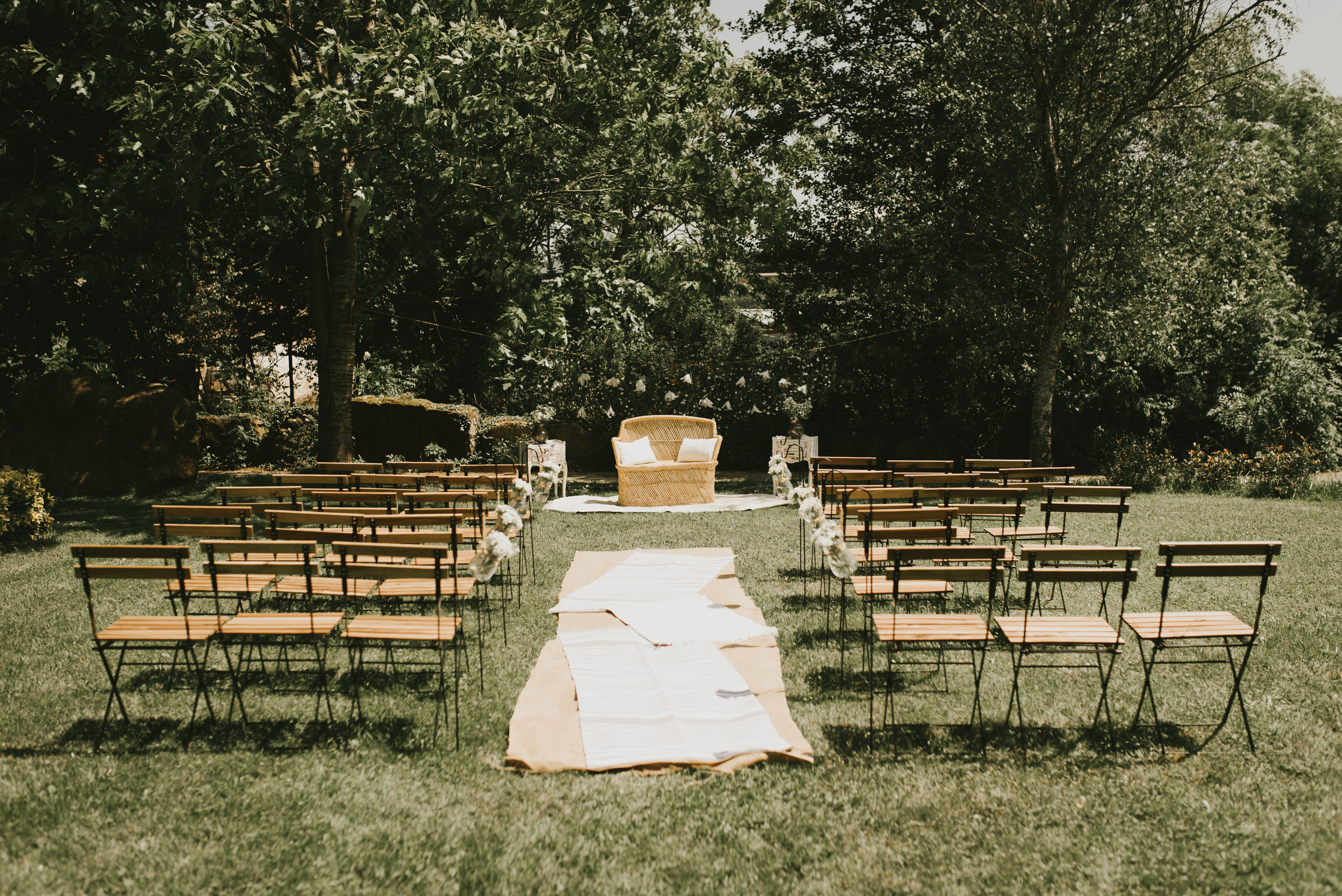 Ceremonia nupcial con sillón doble ratán, alfombras y sillas de forja y madera en entorno natural