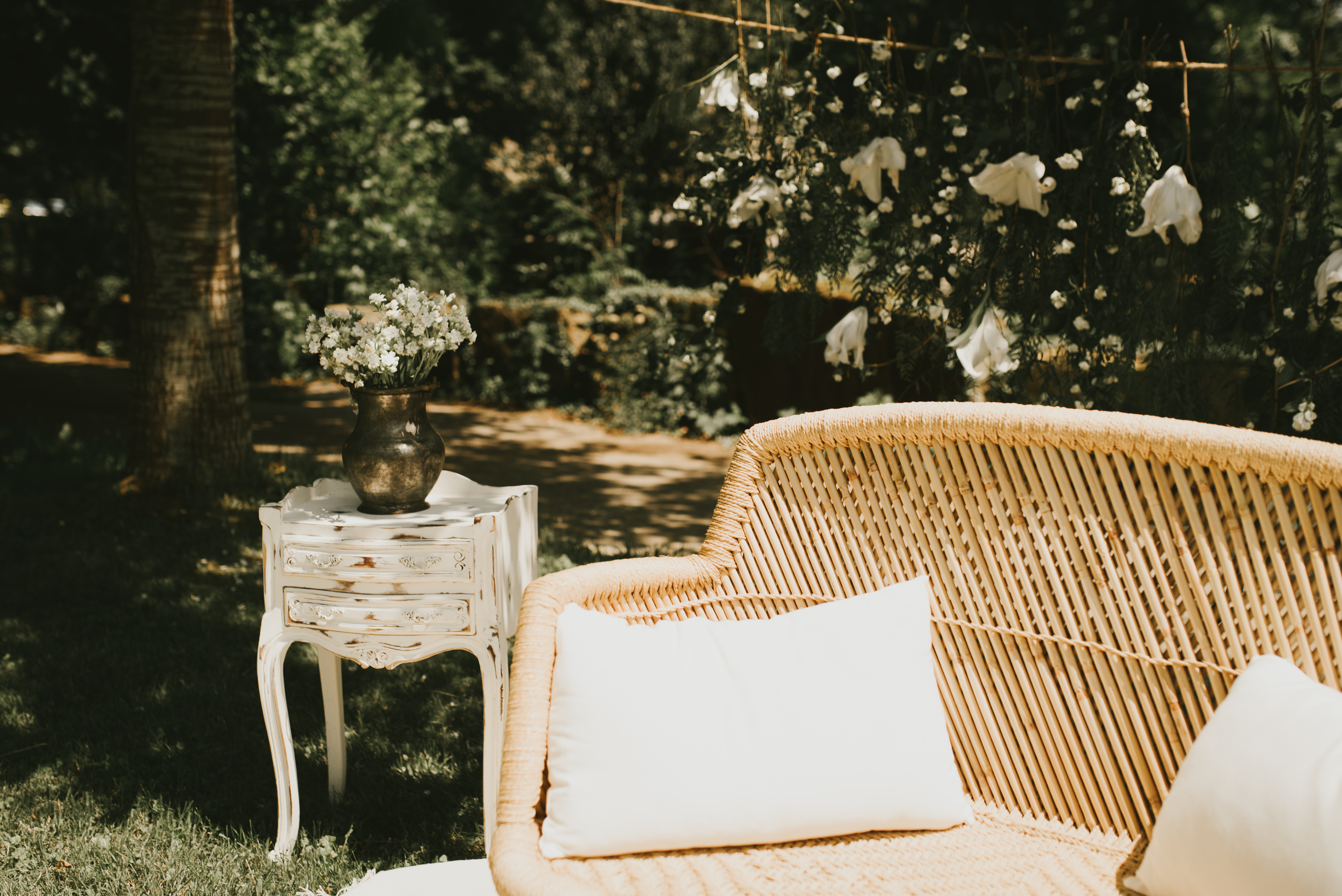 Sillón de ratán con cojines y mesita auxiliar con flores