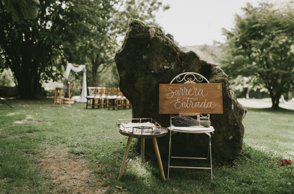 Rincón de bienvenida nupcial, sillas de forja blanca con cartel de entrada y mesa auxiliar