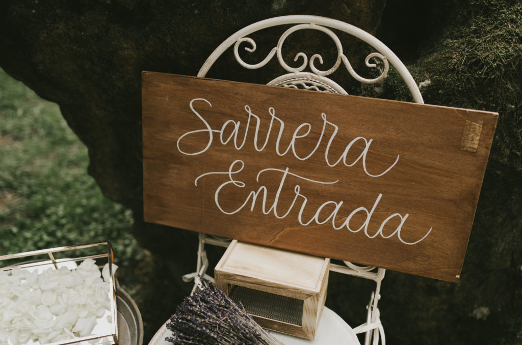 Cartel de entrada - sarrera - sobre silla de forja blanca