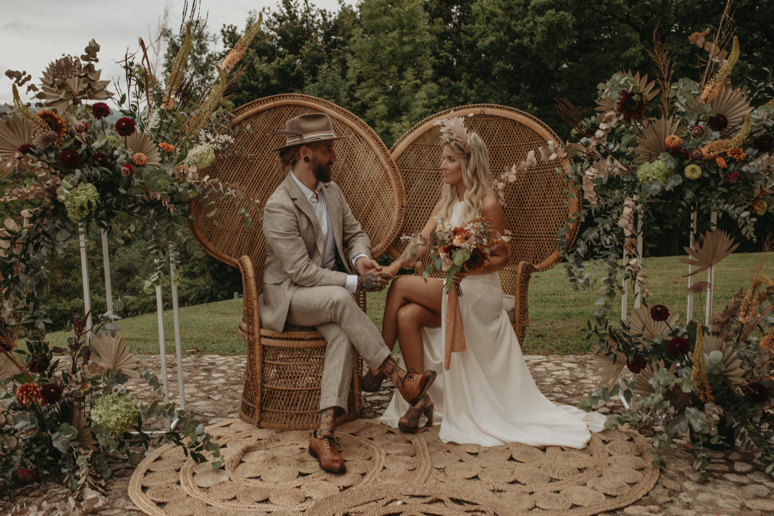 Novios sentados en dos sillones emmanuelle en el altar de la ceremonia