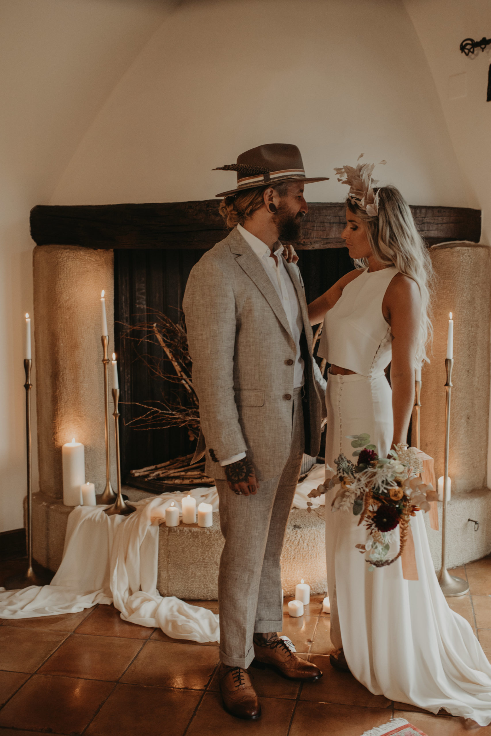 Posado de pareja de novios frente a una chimenea llena de candelabros