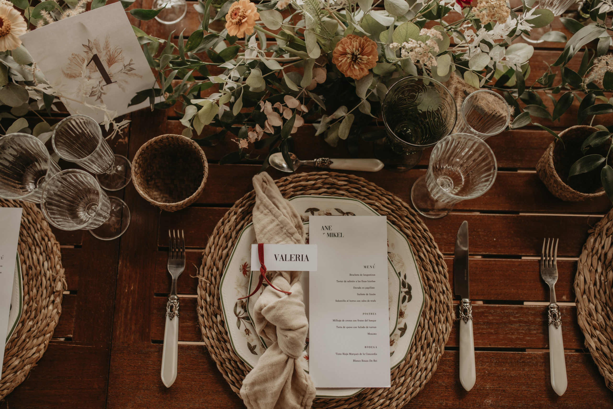 Bajoplato, vajilla, cubertería, copas y decoración floral en un banquete de boda