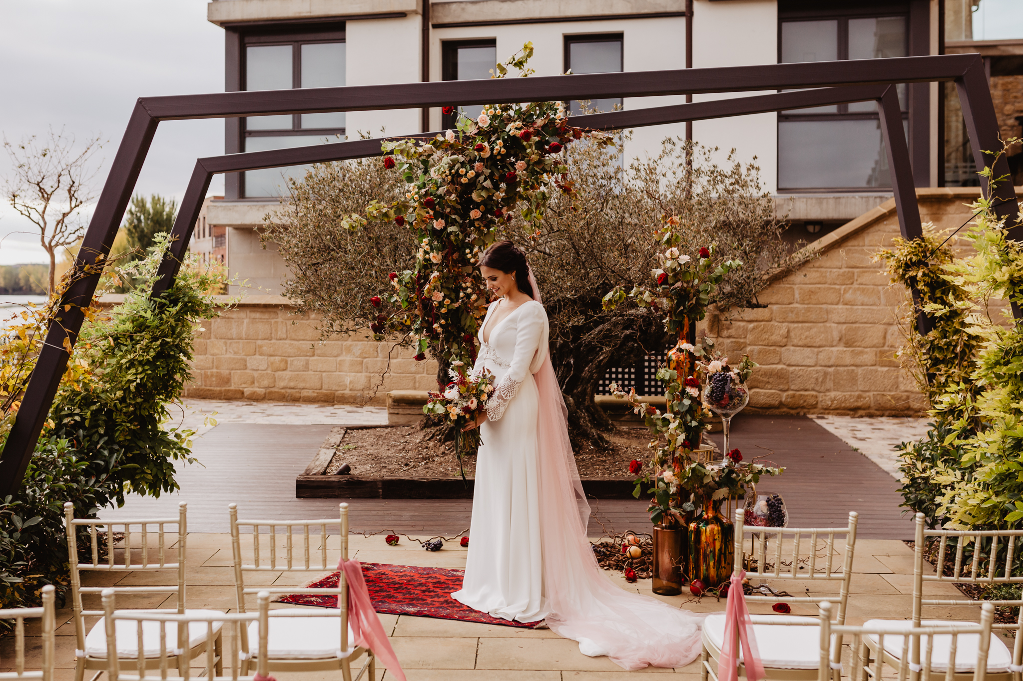 Novia posando en el altar con sillas tiffany doradas para los invitados