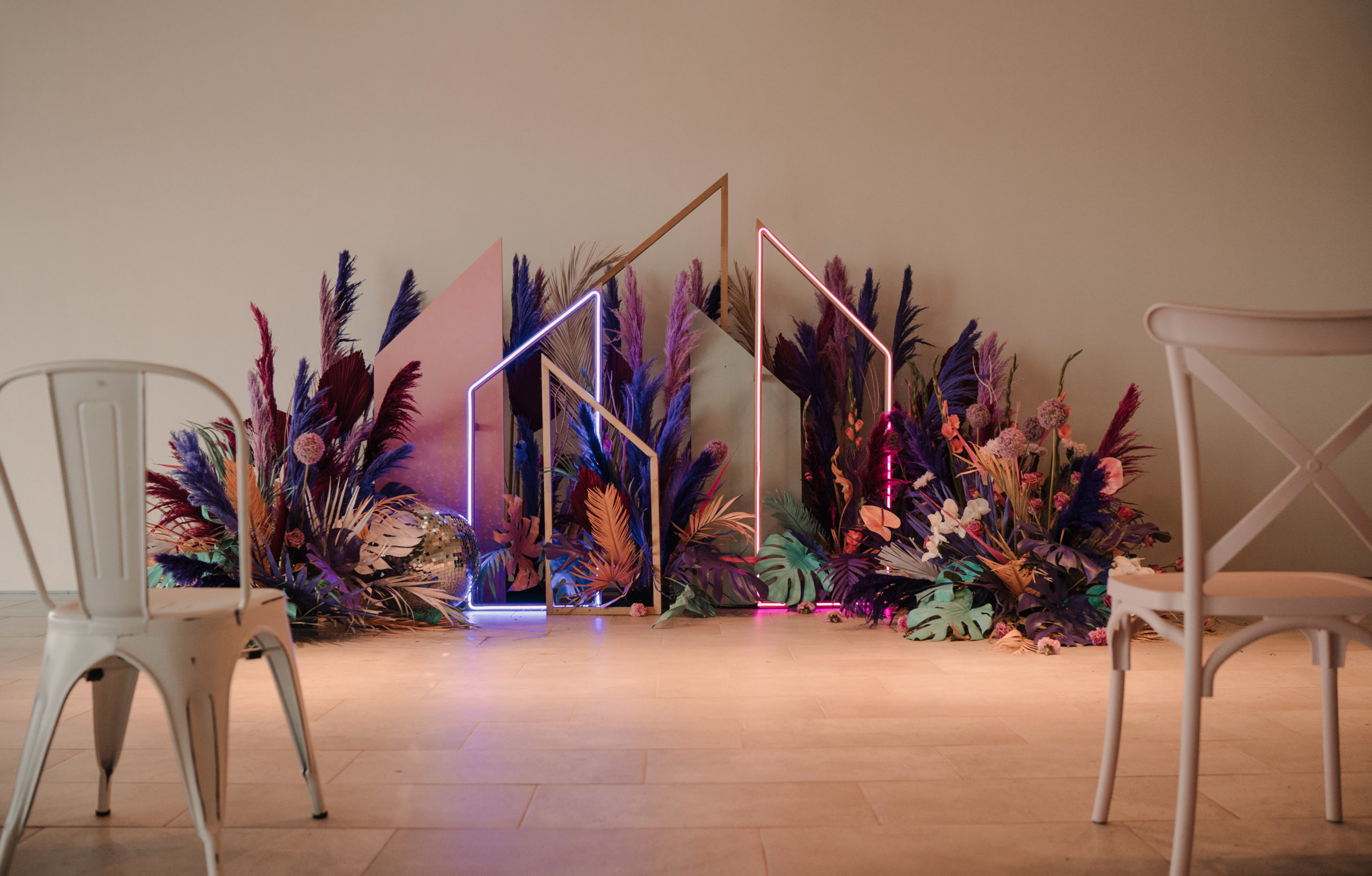 Altar de ceremonia con flores de colores, estructuras geométricas y neones