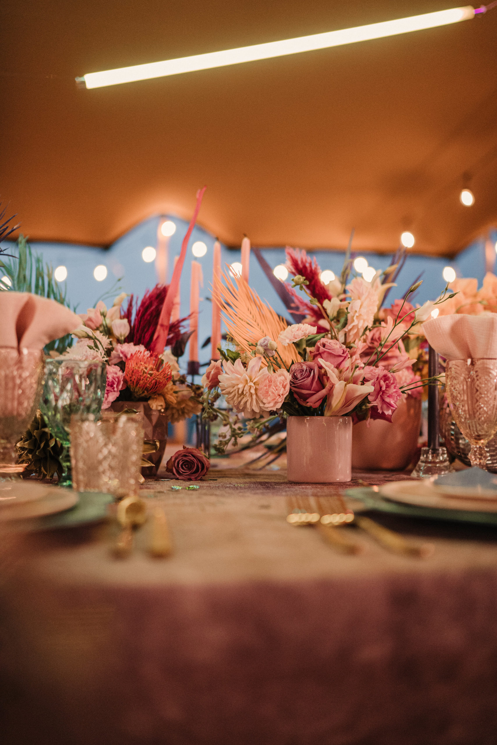 Decoración floral en tonos rosados bajo una carpa con luces