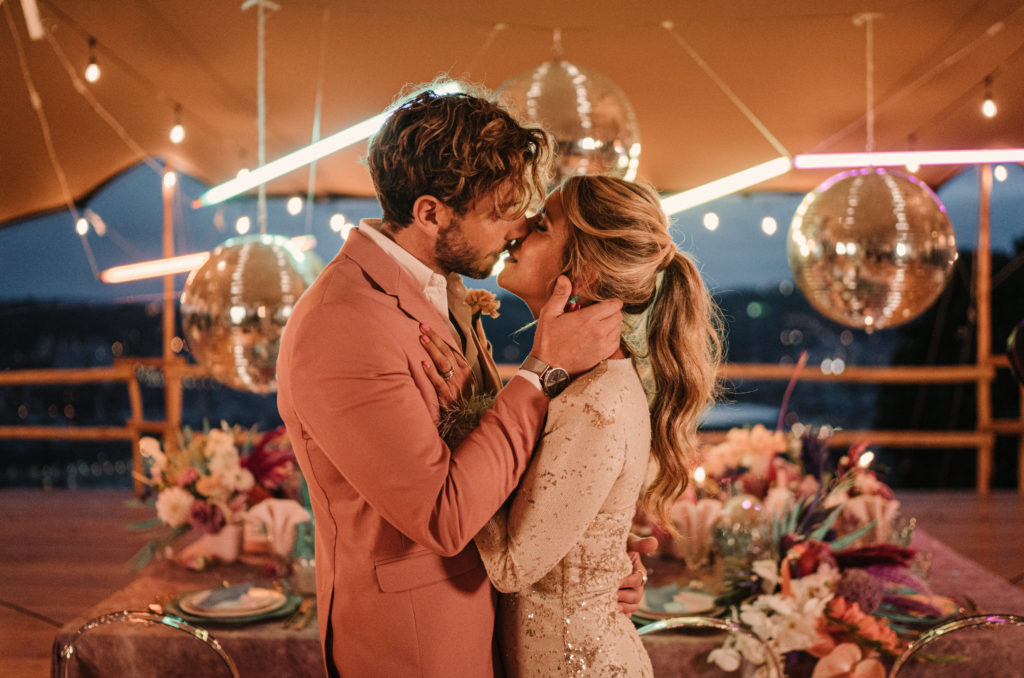 Beso de novio y novia frente a la mesa del banquete