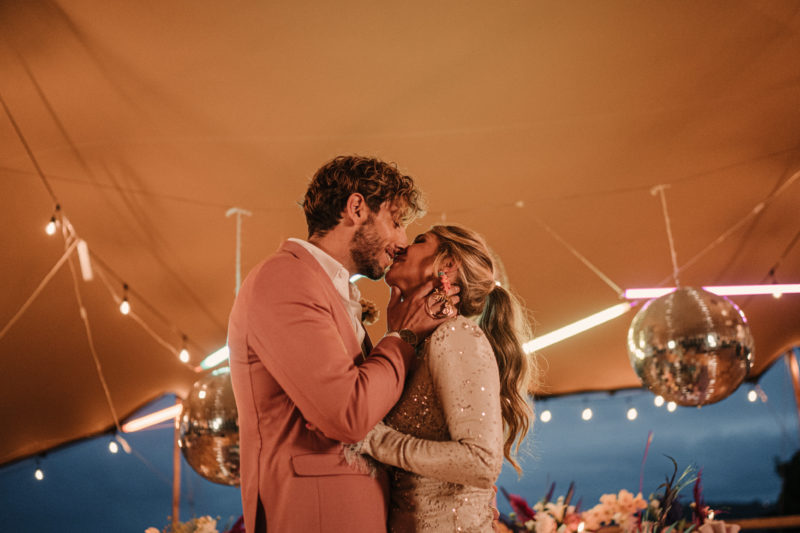 Beso de los novios bajo una carpa