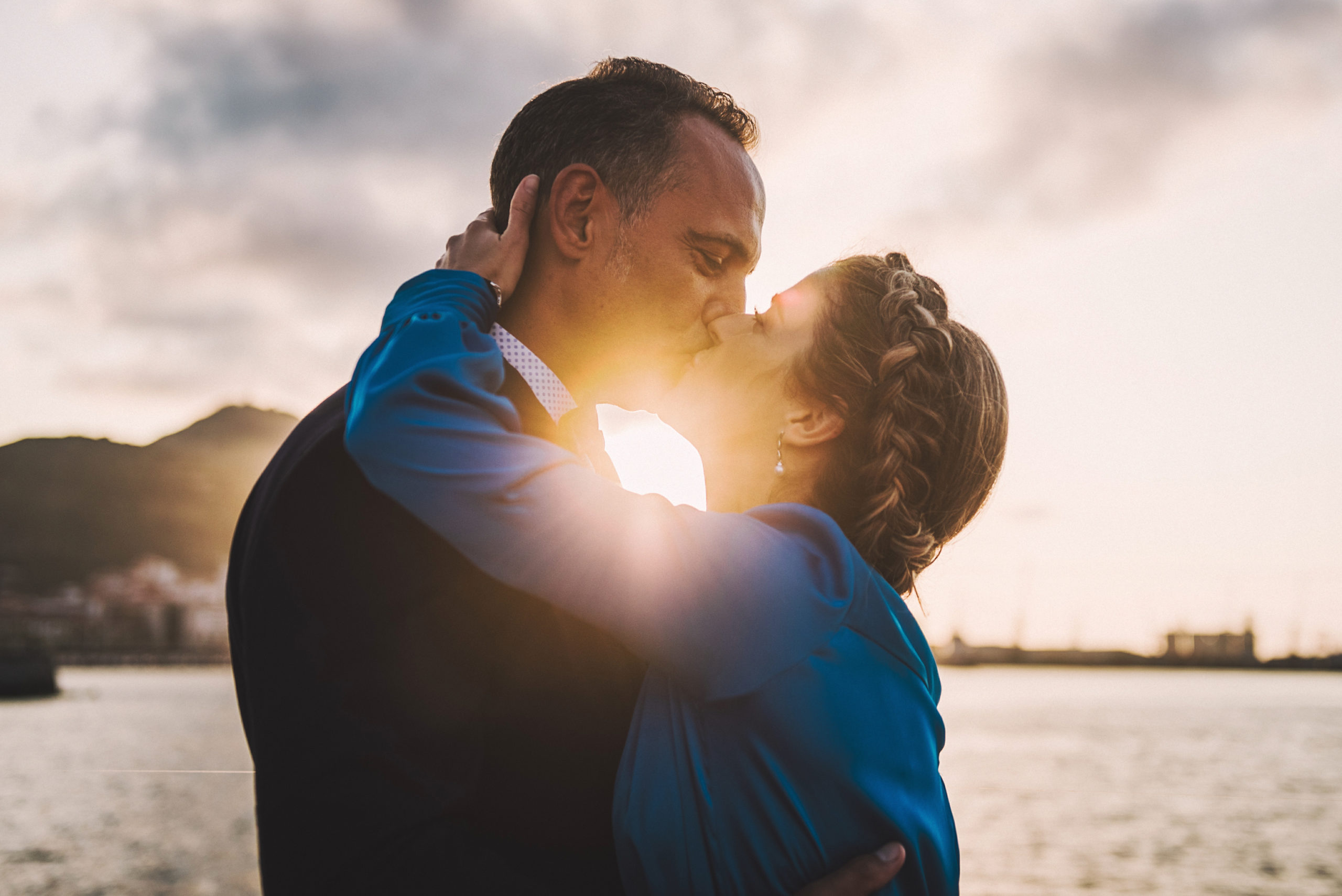 Beso de los novios al atardecer frente al mar