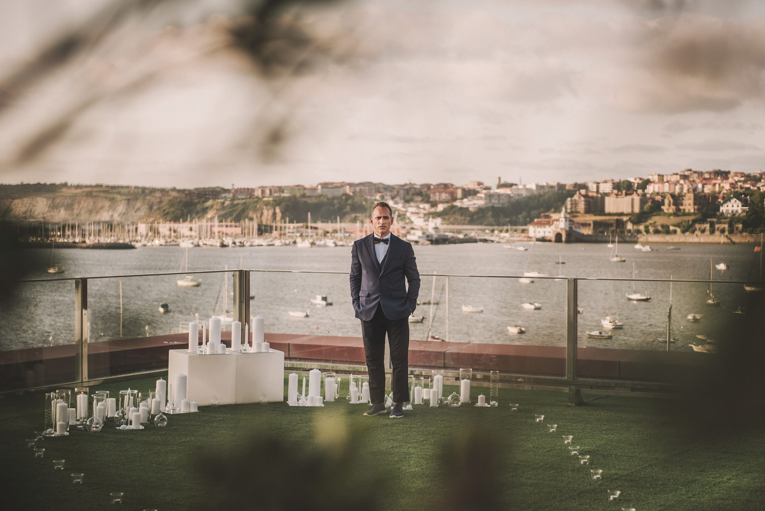 Novio a la espera de novia en un altar con velas frente al mar