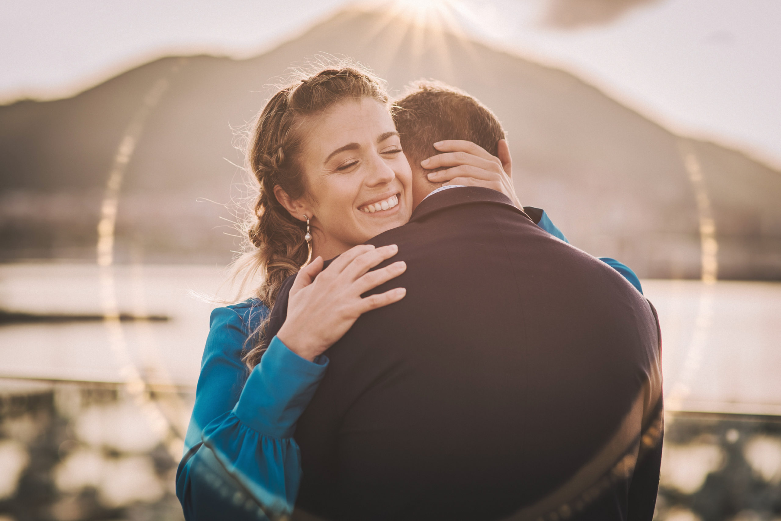 Novia abraza a novio al atardecer frente al mar