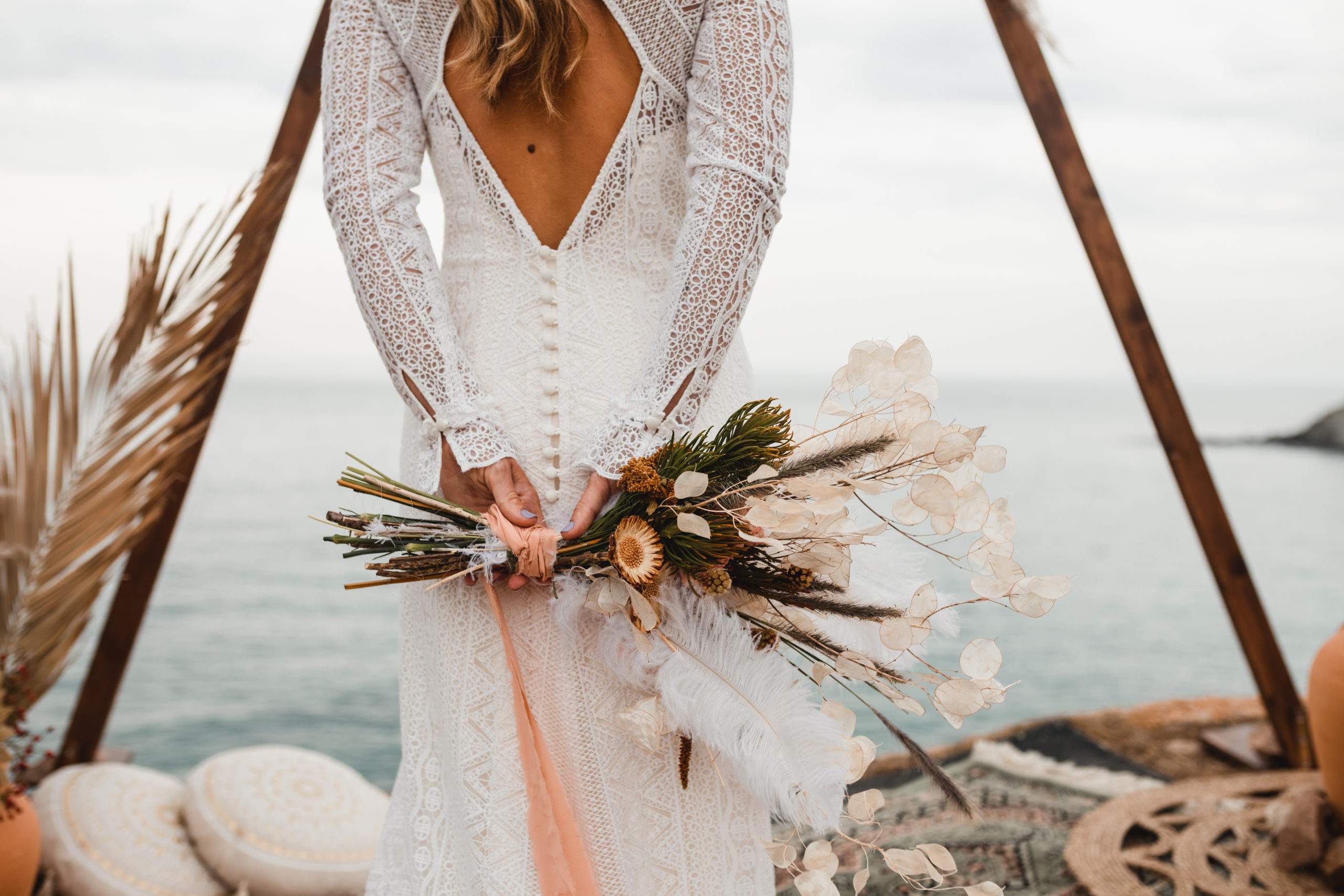 Vestido de espalda descubierta de la novia con un ramo de flores