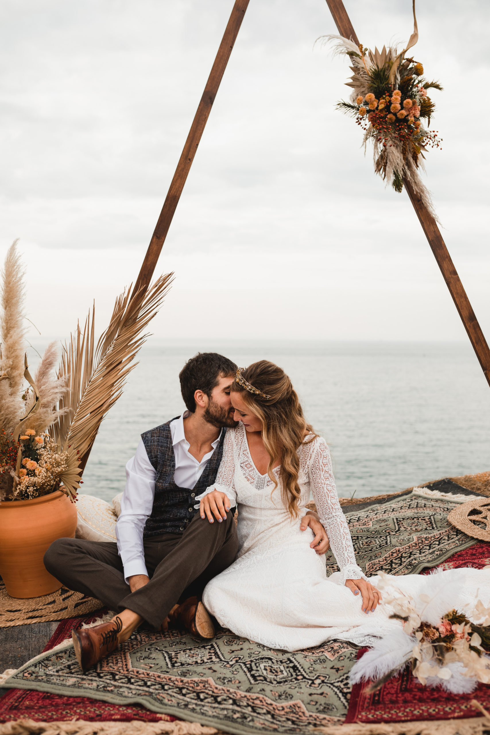 Novios sentados en el altar de la ceremonia nupcial bajo el arco y frente al mar