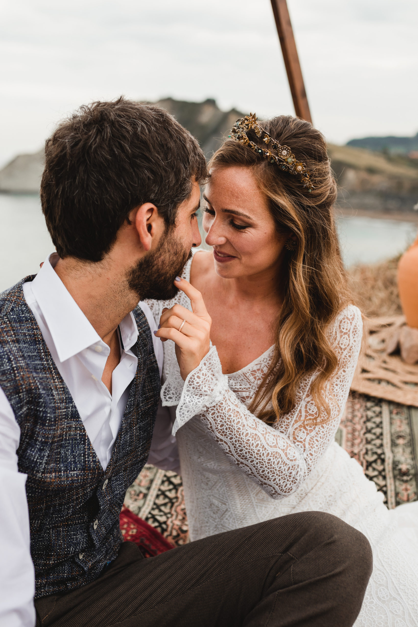 Novia toca los labios del novio sentados sobre las alfombras en la ceremonia nupcial