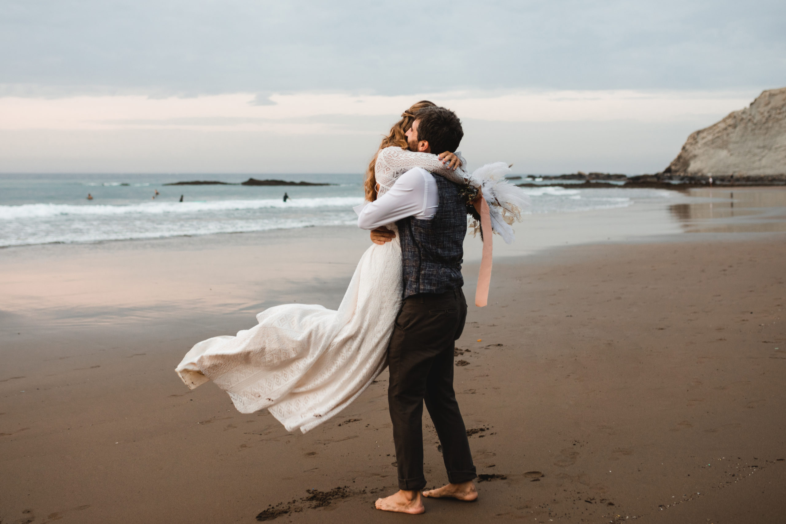 Novio abraza y coge en brazos a la novia en una playa del norte