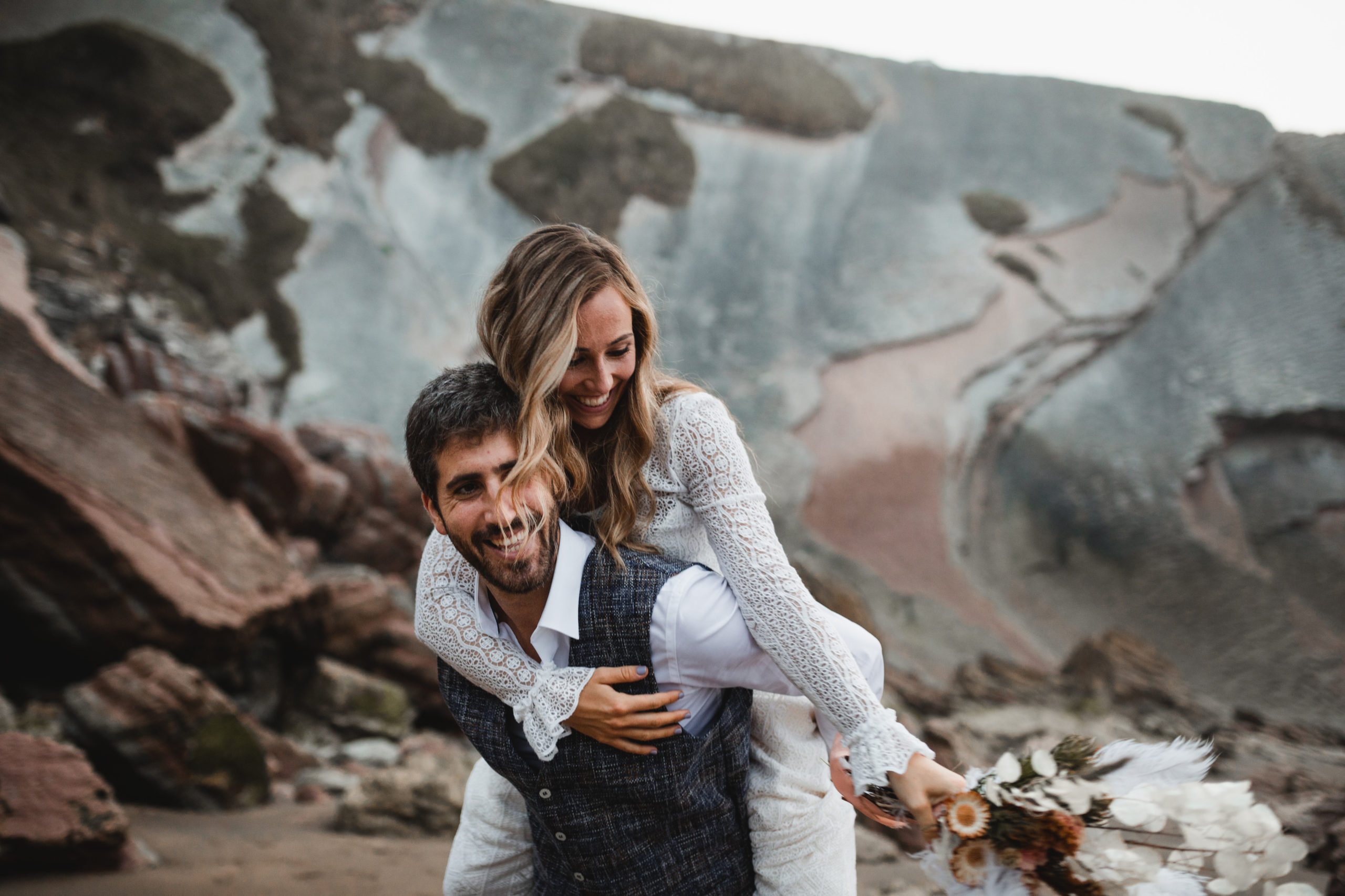 Novia se sube al novio y lo abraza frente a los acantilados de Zumaia