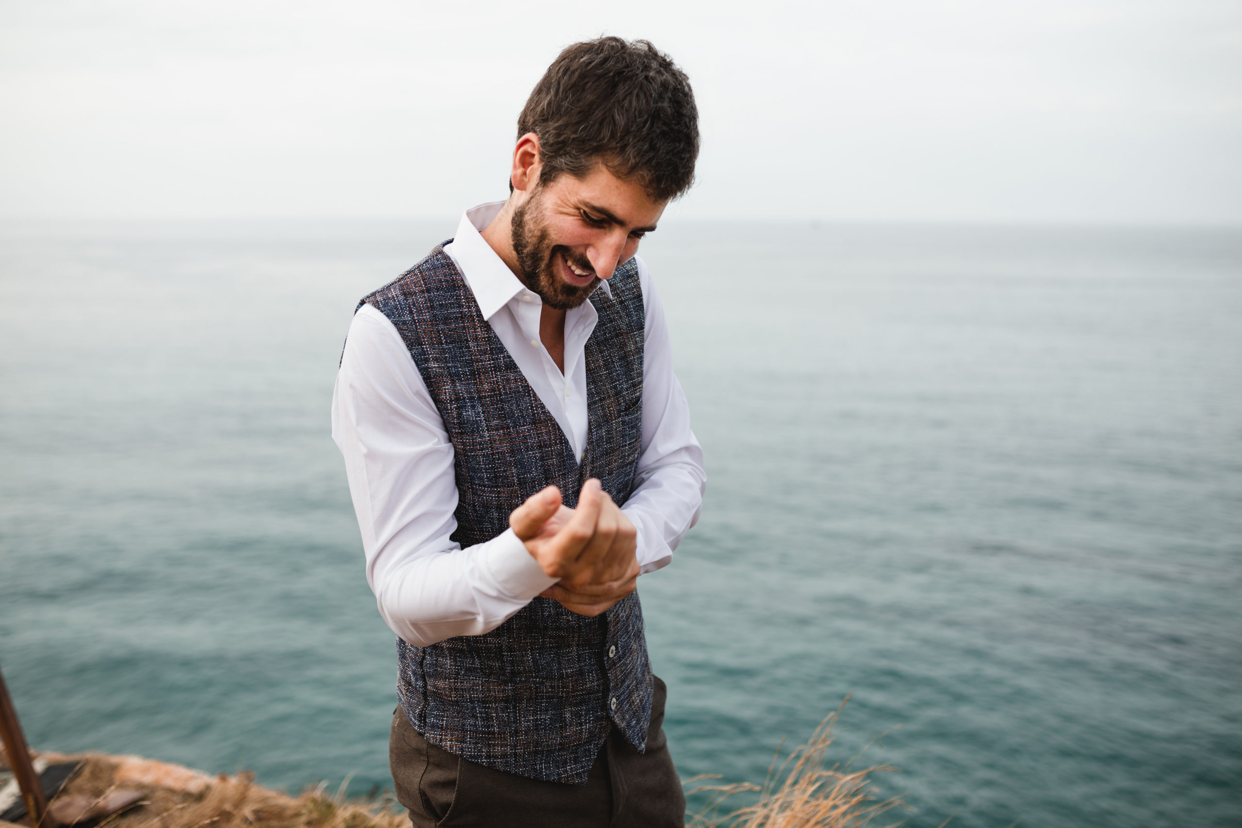 Novio vistiéndose la camisa de su boda con el mar de fondo