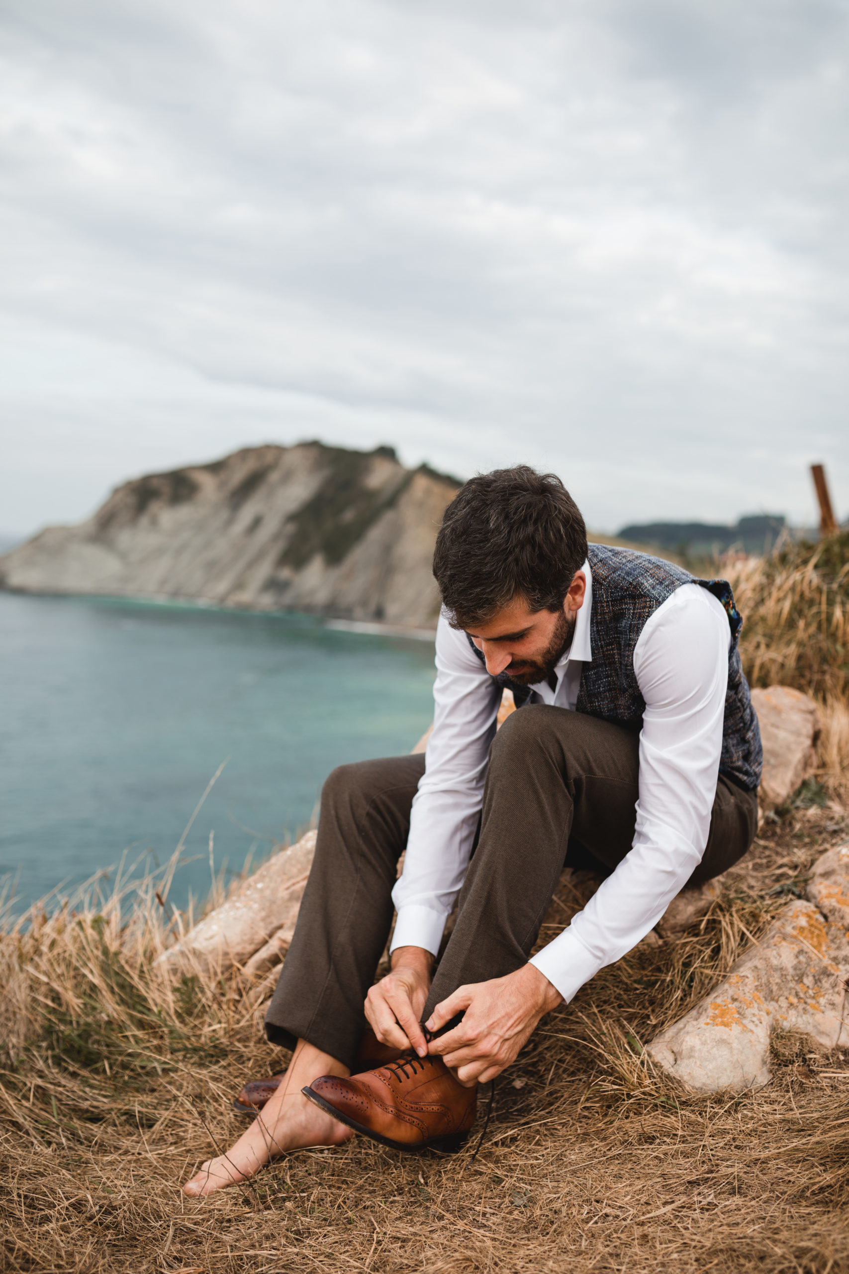 Novio vistiéndose sus zapatos el día de su boda frente al mar