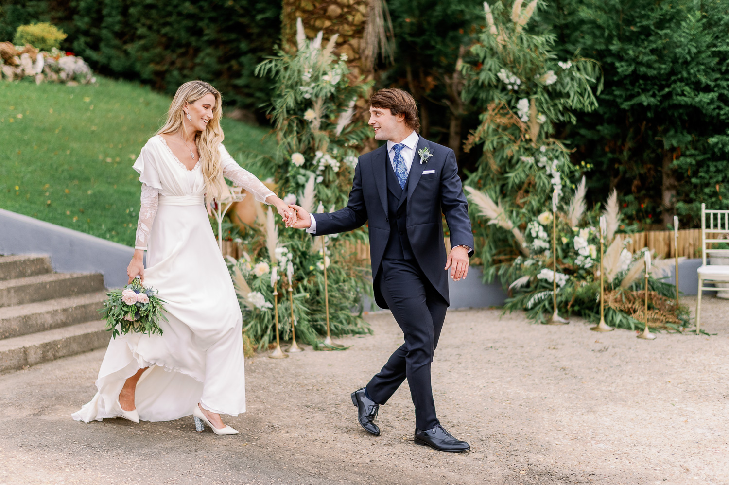 Novia y novio se agarran de la mano hacia el altar nupcial