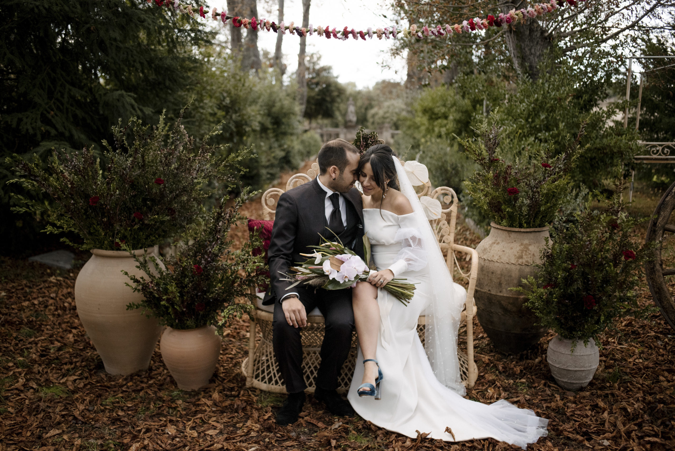 Novia y novio sentados en el sillón ratán pavo real en la ceremonia de boda