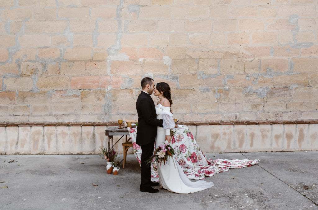 Mesa rústica con mantel floral  moderno en la boda detrás de  pareja de novios